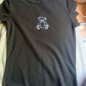 Black short sleeve shirt with a teddy bear in the middle fits on your body